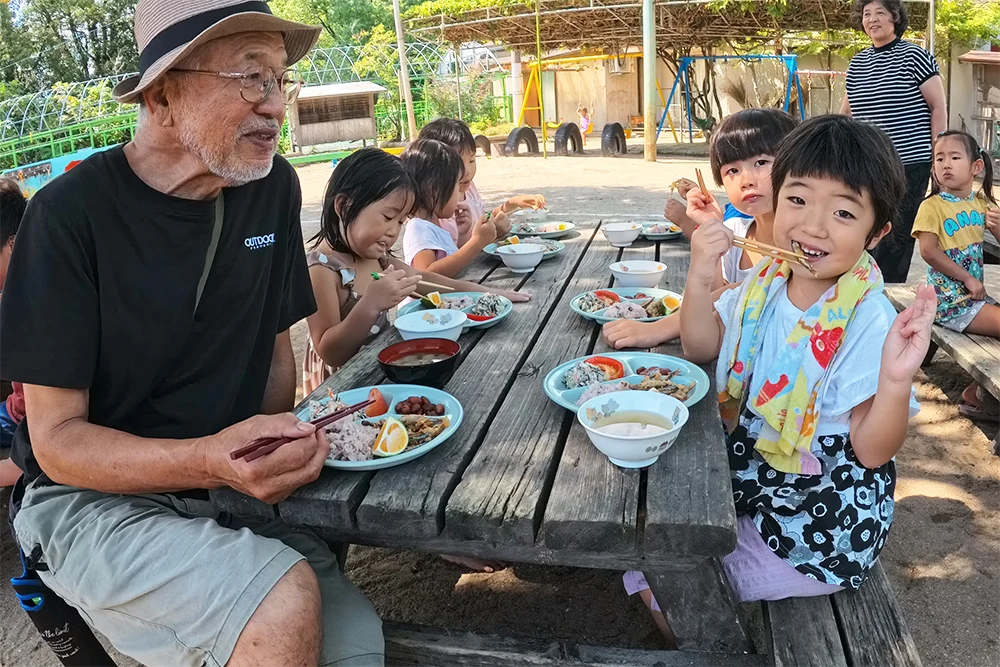 敬老会でおじいちゃんと昼食を食べる子どもたちの様子
