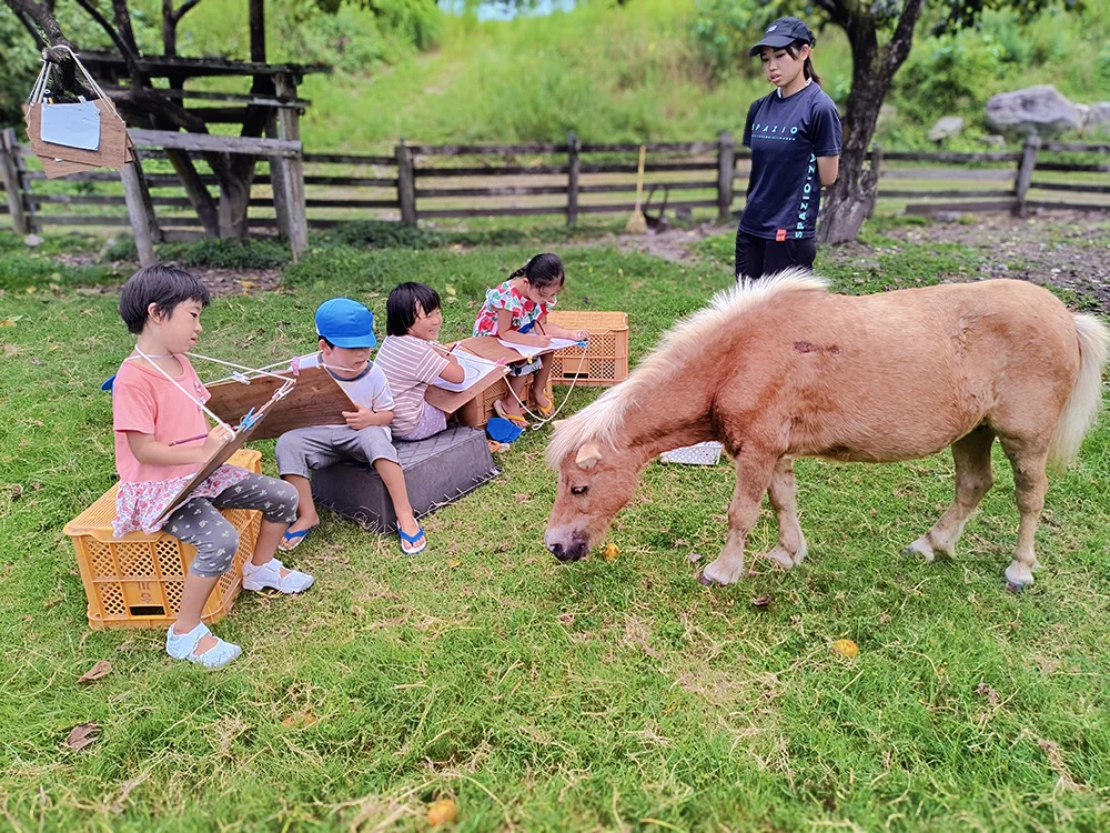牧場で馬に触れ合う子どもたちの様子