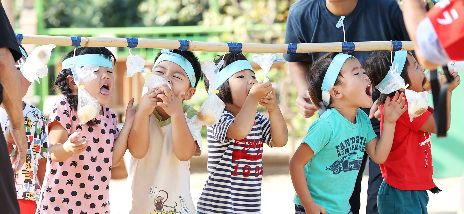 園庭で運動会のパン食い競争をする子どもたちの様子